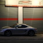 Ασημί Porsche 911 παρκαρισμένη μπροστά από συνεργείο.