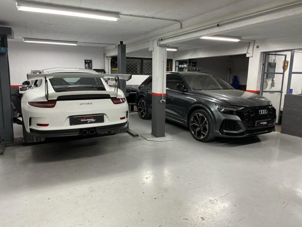 Λευκή Porsche και Audi RS6 παρκαρισμένα στο συνεργείο.