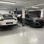 Λευκή Porsche και Audi RS6 παρκαρισμένα στο συνεργείο.